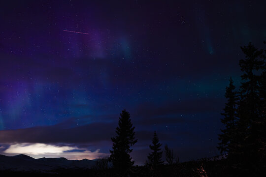 Aurora Borealis Over Mountains and Forest in Norway