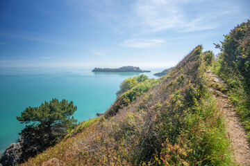 Chemin de randonnée au bord de la mer turquoise en été avec une île à l'horizon. Le chemin de...