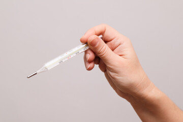 Young woman hands holding mercury thermometer. Measuring temperature.