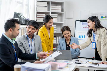 A group of people are gathered around a table with a white board and a laptop