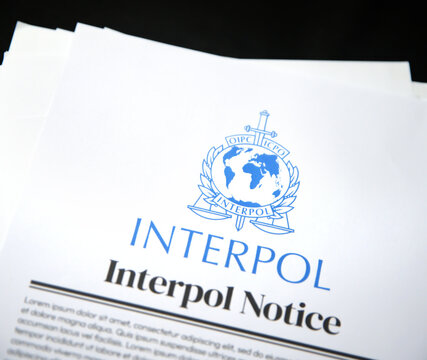 Interpol Notice in paper form placed on black isolated surface background. Illustrative editorial backdrop