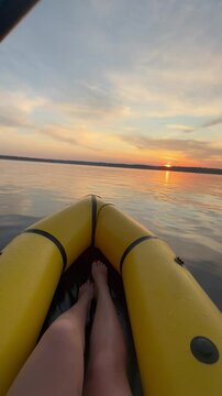 Girl relaxing on a kayak on the sea in the evening at sunset vertical video