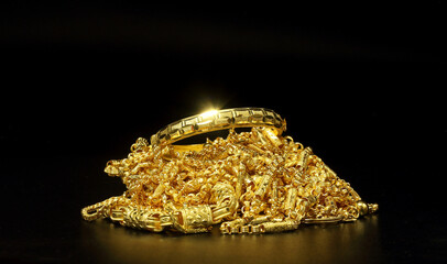 Group of gold jewelry - bracelet, necklace against black background
