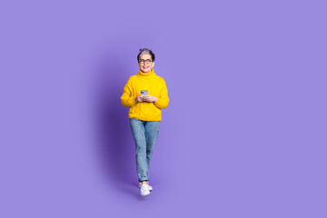 Full length photo of adorable funny woman yellow knitwear typing modern device empty space isolated violet color background