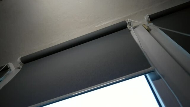 Opening fabric roller blinds on the window. Concept of waking up in the morning.
