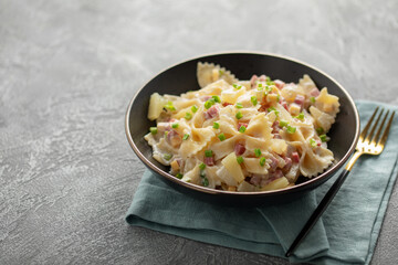 Salad with pasta, ham, pineapple, onion, cheddar cheese with sauce in a bowl on the table. Hawaiian cuisine