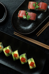 An elegant sushi platter featuring a variety of rolls on black plates