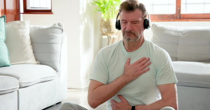 Senior man meditating at home with headphones, finding peace and relaxation