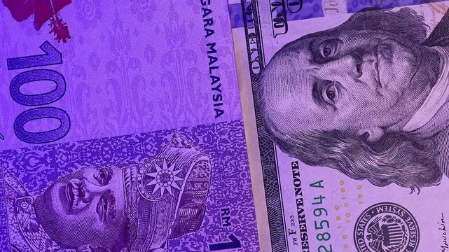 Close up view of rotating 100 Malaysian ringgit (MYR) and 100 USD american dollars under the flashing light of a police siren, brand new notes. Selective focus. Concept of financial crime in Malaysia.