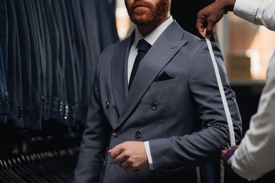 Luxury designer atelier, professional tailor measuring customer for bespoke suit in menswear store