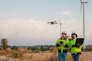 Engineer and technician is flying drones to inspect wind turbine installation sites to produce enough renewable energy.