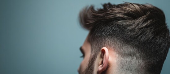 Obraz premium Closeup of stylish man's haircut with textured brown hair and trendy fade on blue background featuring ample empty space for text or design.