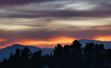 Rosso tramonto sulle montagne da dietro agli alberi