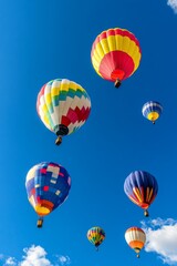 Fototapeta premium A vibrant scene of colorful hot air balloons floating against a clear blue sky, creating a joyful and uplifting atmosphere.