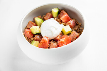 A delicious bowl of hearty grain topped with diced tomatoes, zucchini, and a perfectly poached egg. Ideal for a healthy breakfast or lunch option. Fresh and nutritious meal.