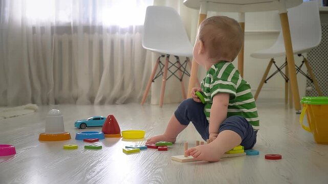 Toddler boy is playing with educational geometric sorter at home. Early development concept. Slow motion. 4k