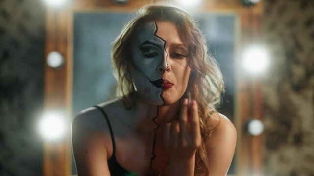 Sexy lady with makeup of comics character playing role in theatrical performance . Portrait of professional actress smoking alone in dressing room, backstage of movie filming, duality of personality