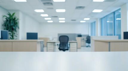 Blurred modern office interior with empty desk in foreground.