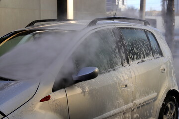 Gray car at self-service car wash. Washing car with cleaning soap