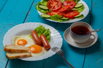 Breakfast fried eggs with sausages crispy white bread and salad with tomatoes