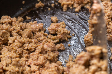 Frozen ground beef is fried with onions in a frying pan with vegetable oil