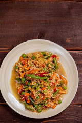 Couscous with vegetables in sauce on a plate on the table next to a fork