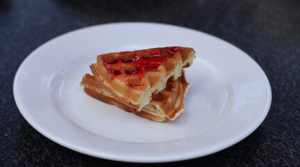 waffles with strawberry jam on white plate for brakfast