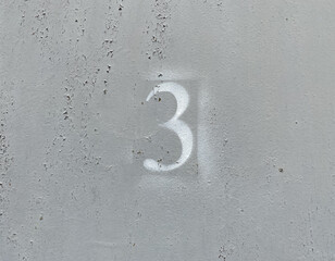 White number 3 on aged background. Three on textured gray surface 