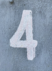 White number 4 on aged gray background. Four on textured surface with old paint