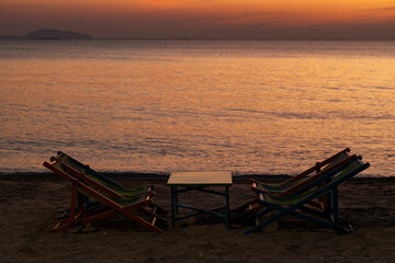 Silhouette of a chair at sunrise on a beautiful beach in Thailand.