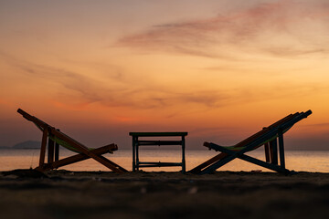 Silhouette of a chair at sunrise on a beautiful beach in Thailand.
