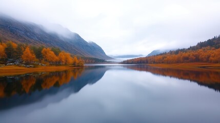 Naklejka premium Tranquil Lake in Misty Morning with Autumn Colors Reflecting Mountains and Forest