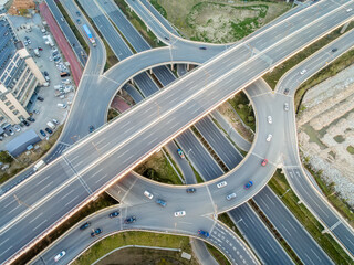 Top view of multi-level highway intersection with cars driving under clear sky