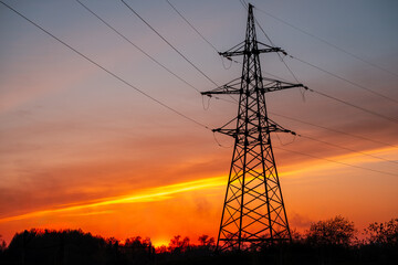 A tall power tower is silhouetted against a beautiful sunset