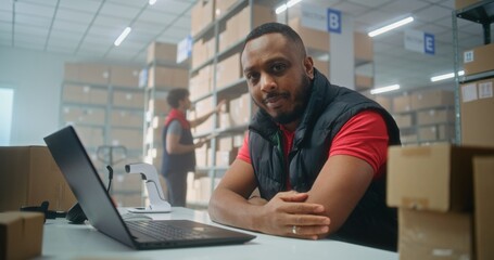 Portrait of African American post office employee scanning parcel with barcode scanner, using...