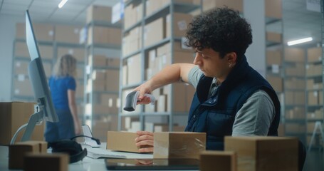 Male inventory manager works on computer, scans parcels with barcode scanner, prepares package for shipping to customer. Sorting center employees carrying boxes. E-commerce store or postal service.