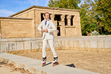 Man in a suit rollerblading near an ancient stone temple outdoors