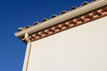 Gouttière aluminium beige sable sur la façade de la maison, descentes rectangulaires et génoise...