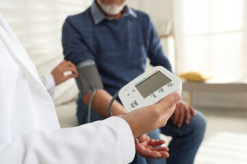 Doctor measuring patient's blood pressure in hospital, closeup