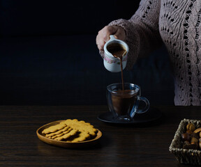 Woman pouring hot chocolate into a transparent cup