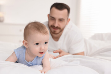 Father with his cute baby on bed at home, selective focus