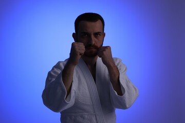 Karate fighter in uniform on blue background