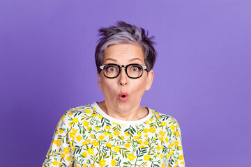 Surprised woman with glasses against purple background wearing floral shirt