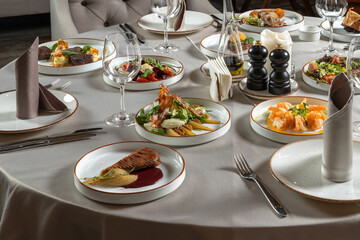 The holiday table is set for a big company dinner. Duck breast, shrimp and other luxury food