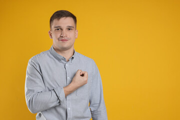 Man making promise on orange background, space for text. Oath gesture
