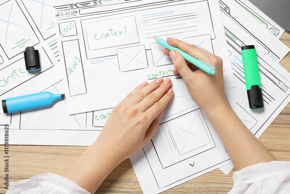 Poster website designer creating wireframe on paper with pen at wooden table, top view