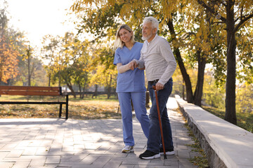 Fototapeta premium Caregiver assisting senior man in park. Home health care service