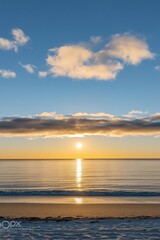 Obraz premium Serene sunrise over the Pacific Ocean at a beach in Oregon, USA, showcasing a tranquil seascape with soft waves and a clear sky.