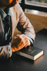Portrait of a man praying with a Bible on a table. Confession concept. Pray and talk with God.