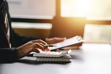 Accountant working at desk using calculator to calculate company's annual financial and tax report....
